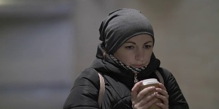 冬天，漂亮女人在隧道里取暖，喝着热咖啡