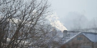 烟从房子的烟囱里冒出来。屋顶上的管子。冬天的寒冷