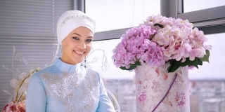 美丽的穆斯林新娘穿着美丽的婚纱，闻着花香