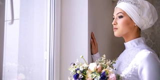 美丽的穆斯林新娘化妆看着窗外和微笑