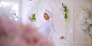 美丽的穆斯林模特在白色婚纱与穆斯林头饰摆姿势在工作室