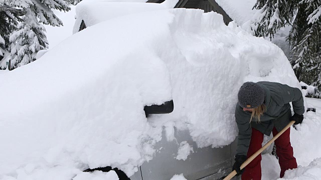 在车前铲雪的女人。