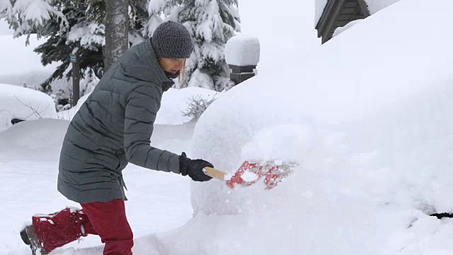 在车前铲雪的女人。