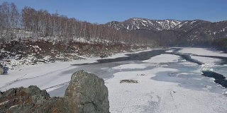 在冬季，在Elekmonar定居点附近的阿尔泰河Katun的视频全景图，背景是水和山中漂浮的冰