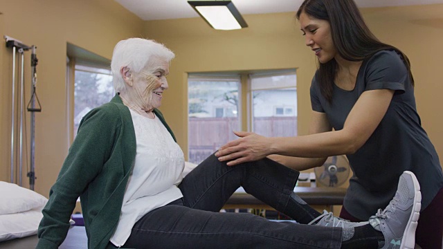理疗师按摩老年女性的小腿肌肉