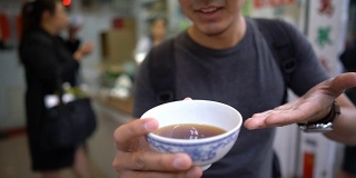 亚洲人在镜头前展示和品尝著名的中国凉茶