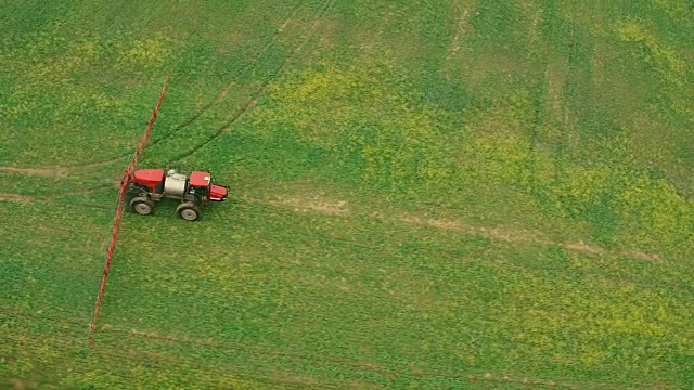 天线。用油菜飞过田野。农用拖拉机喷洒夏季油菜田