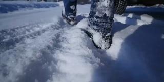 双脚在深雪中行走的慢镜头。徒步旅行者的脚步。冬季户外休闲活动