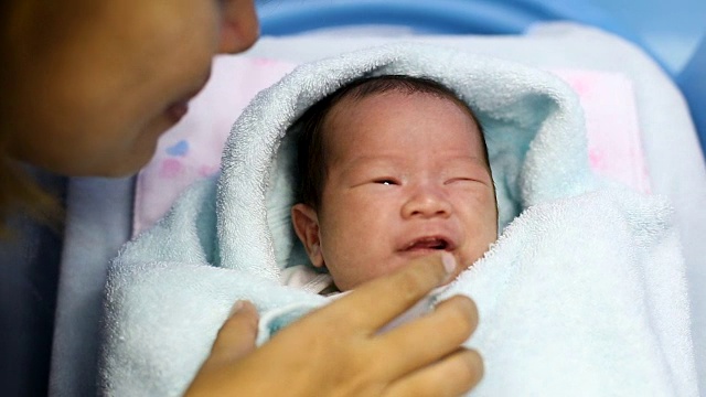在医院的产房里，年轻的母亲抱着她刚出生的亚洲宝宝哭泣