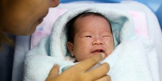 在医院的产房里，年轻的母亲抱着她刚出生的亚洲宝宝哭泣