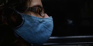 一名戴着面罩坐在地铁窗口旁的男子