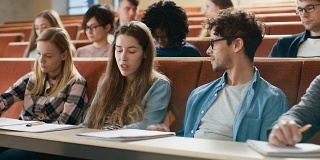 一男一女在大学教室里交谈，他们是同班同学听一场讲座。