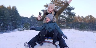 妈妈和儿子在雪山上用手机拍自己的照片