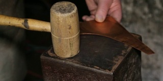 在一个铜匠的车间:铜匠用锤子敲打
