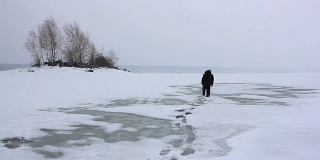 俄罗斯鄂毕河水库，一名背着背包的男子在暴风雪中行走