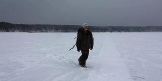 俄罗斯鄂毕河水库，一名背着背包的男子在暴风雪中行走