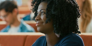 一个聪明美丽的年轻黑人女孩在一间满是多民族学生的教室里听讲座的肖像。年轻人在大学学习。