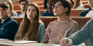 在教室里聪明的亚洲学生问教授一个问题。多元种族的现代聪明学生在学院。