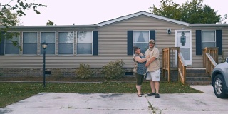 幸福沉重的夫妇拥抱在一个制造的家前面