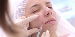 在美容水疗中心给一个女人做痛苦的美容手术。特写医生双手戴上手套做针眼治疗，矫正鼻唇沟。美丽的行业