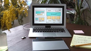 Web开发人员坐在桌子前绘制未来网站的草图。在家办公远程办公视频素材模板下载