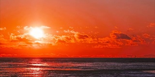 在白雪覆盖的海湾上延时拍摄红色日落