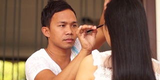 化妆师给一个年轻女子画眉毛。景深浅