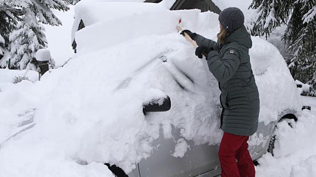 在车前铲雪的女人。