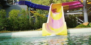 兴奋的年轻女子滑下水上滑梯在有趣的水上公园尖叫在一个炎热的夏天。缓慢的运动。1920 x1080