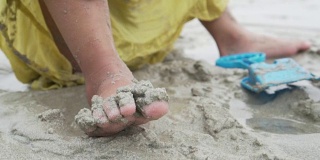 光着脚的小女孩在沙滩上玩沙子的慢镜头