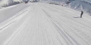 在阳光明媚的天气里，滑雪者沿着斜坡快速地滑下滑雪道
