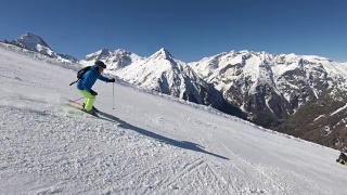 在阳光明媚的冬日，高山滑雪者在滑雪场滑雪视频素材模板下载