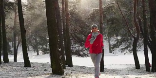跑步运动的女人。女跑步者在寒冷的冬天的森林里慢跑，穿着暖和的运动服和手套。美丽合体的女性健身模特。