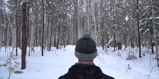 一个男人在冬天在森林的小路上奔跑。从后面看。