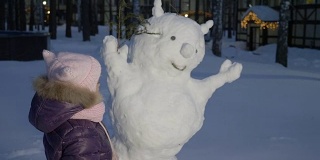 小女孩在雪地里堆雪人，看着它