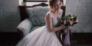 年轻的新娘手捧花束坐在椅子上