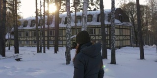 在冬日的阳光下漫步在白雪覆盖的公园里的女人