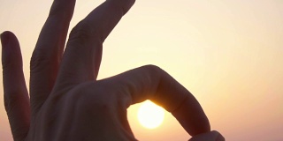在日落天空的映衬下，用慢动作展示手势、手势、符号可以