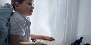 学校的盲人，可爱的孩子坐在房间的窗台上阅读盲文字体