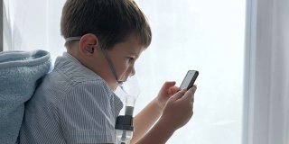 吸入药物后，男孩用口罩从吸入器中拿起手机放入手中