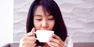 亚洲女人在咖啡厅喝咖啡与快乐的情绪。