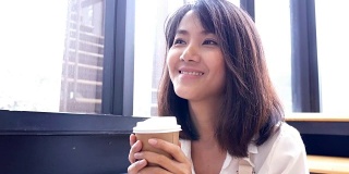 亚洲女人在咖啡厅喝咖啡与快乐的情绪。