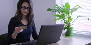 网上购物，商务女士用信用卡通过笔记本电脑在办公室进行网上支付