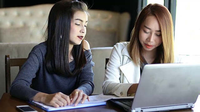 亚洲商务女性使用笔记本工作和讨论重要的合同在办公室