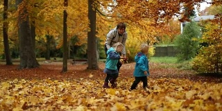 童年时光:少年和孩子们在公园里与秋叶嬉戏