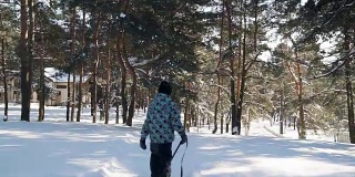 在阳光明媚的冬日里，小男孩拉着雪橇上山。