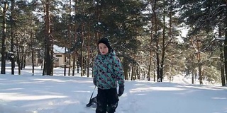 在阳光明媚的冬日里，小男孩拉着雪橇上山。