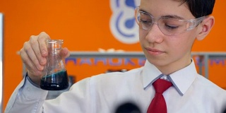 在化学课上，一个男生在研究试管，做实验。