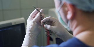 从个人角度看，医生在手术前用无菌手套夹住手术刀片。POV特写医疗器械在手，从后面看，设备在一个诊所和医院没有病人