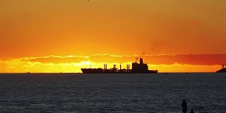 在4k慢镜头的夕阳下，一艘集装箱货轮在海上航行